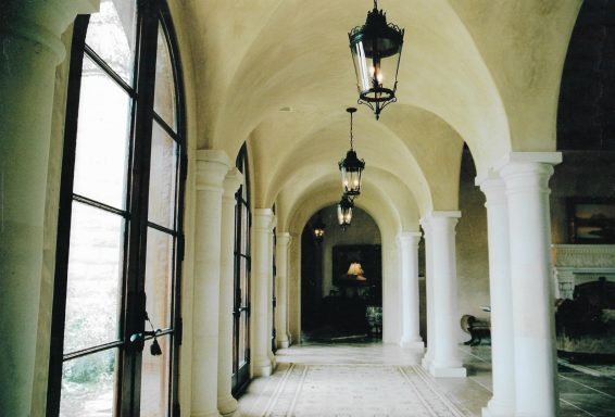 Interior hallway with arched ceilings, columns, and hanging lanterns.