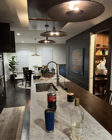 Modern kitchen with a marble island, drinks, and pendant lighting.