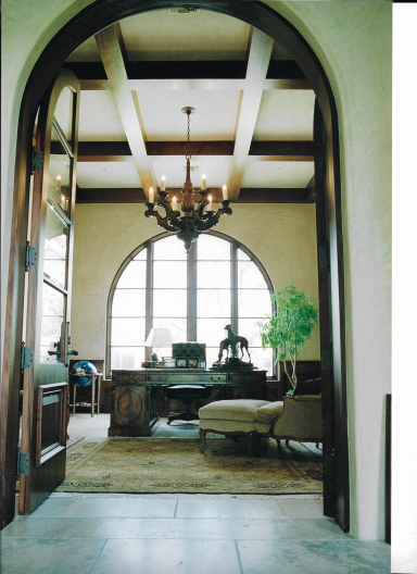 Interior view of a room with an arched doorway, chandelier, and a cozy seating area.