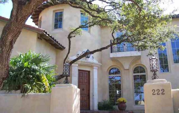 Two-story house with a curved entrance, large windows, and a tree in front.